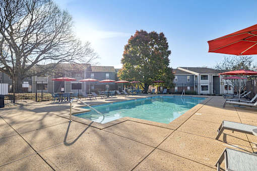 A pool area with sun loungers and umbrellas.