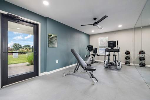 A gym room with a row of exercise machines and a chair.
