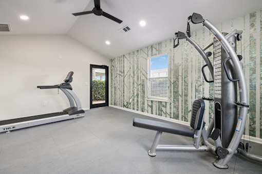 A home gym with a treadmill, a rowing machine, and a bench.