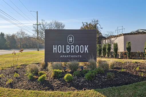 A sign for Holbrook Apartments is displayed in a landscaped area.