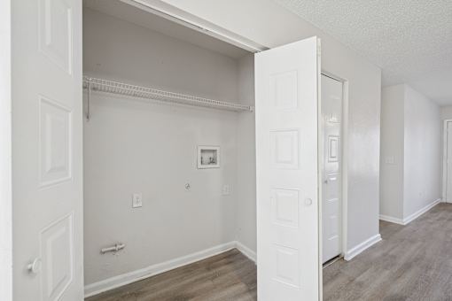 A white door is open to a room with wood flooring.