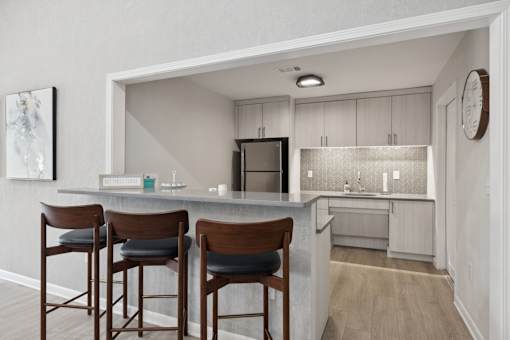 A kitchen with a bar area and chairs.