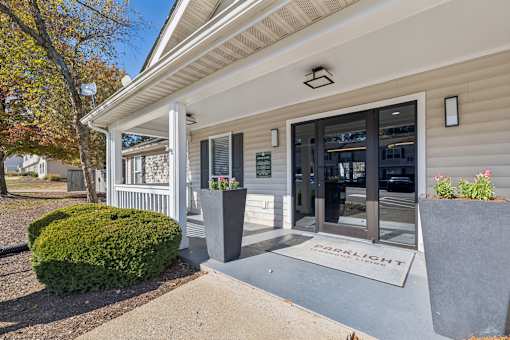 A building with a white porch and a sign that says "COSMOLIT" on the mat.