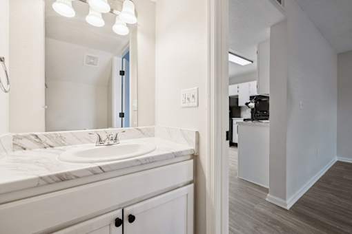A bathroom with a marble countertop and a white sink.
