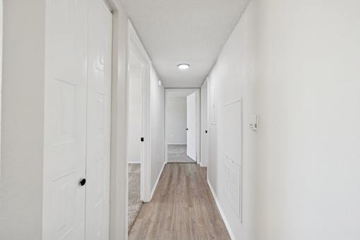 A long hallway with white walls and wood flooring.