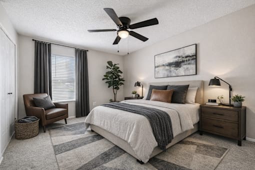 A bedroom with a large bed, a ceiling fan, and a painting on the wall.
