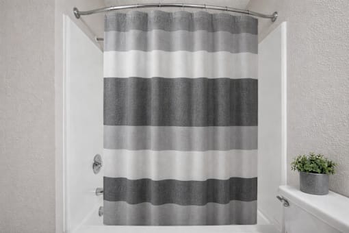 A grey and white striped shower curtain in a bathroom.