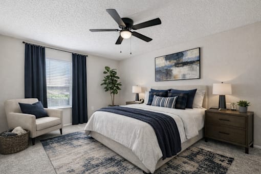 A bedroom with a large bed, a ceiling fan, and a painting on the wall.