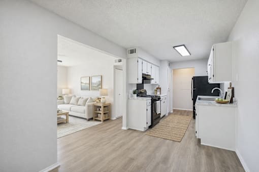 A kitchen with white cabinets and a black fridge is shown.