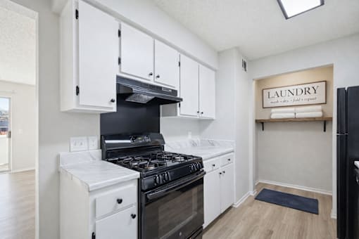 A laundry sign is on the wall in a small room with a black refrigerator.