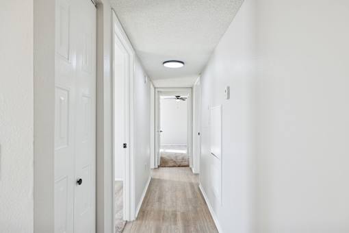 A long hallway with white walls and wood flooring.