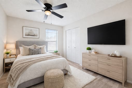 A bedroom with a bed, dresser, and ceiling fan.