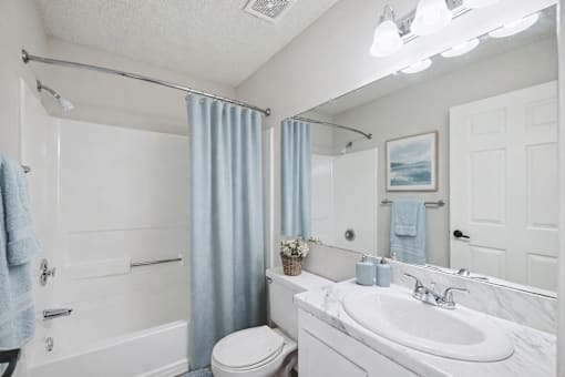 A bathroom with a white toilet, sink, and shower.