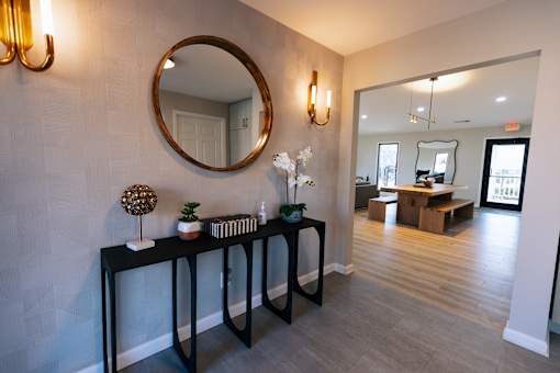 A hallway with a mirror and a table with objects on it.