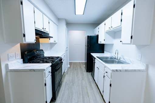 A kitchen with black appliances and white cabinets.