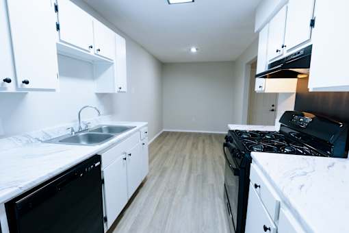 A kitchen with white cabinets and black appliances.