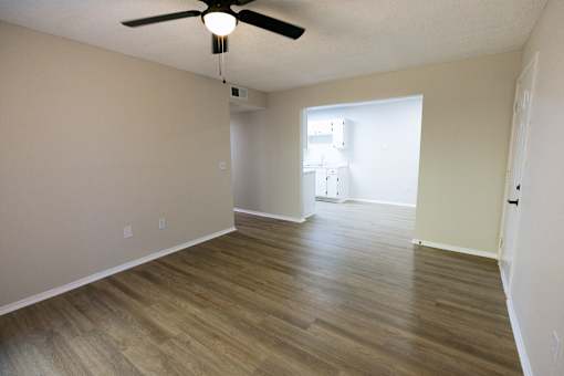 A room with a ceiling fan and wooden flooring.