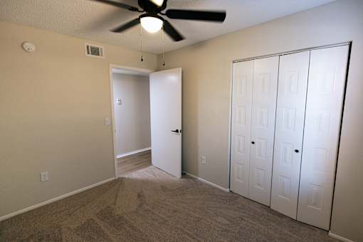 A room with a ceiling fan and a white door.
