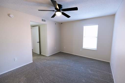 A room with a ceiling fan and carpeted floor.