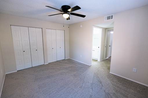 A room with a ceiling fan and carpeted floor.