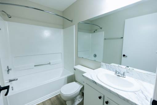 A white bathroom with a toilet, sink, and bathtub.