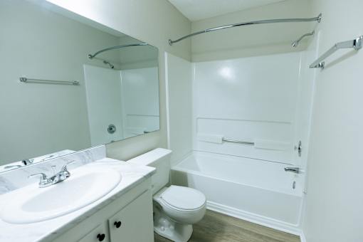 A white bathroom with a toilet, sink, and bathtub.