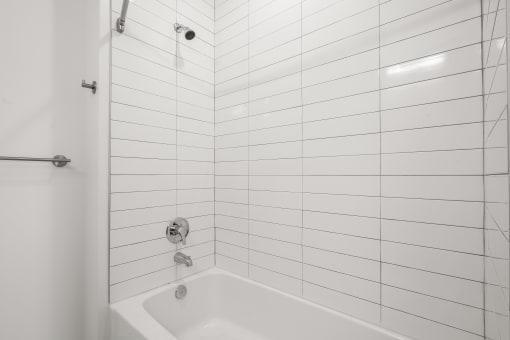 a bathroom with white tiled walls and a white bathtub