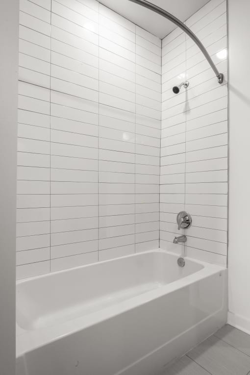 a bathroom with white tiles and a white bathtub