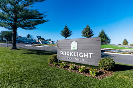 A sign for Parklight Townhomes is displayed in a grassy area.