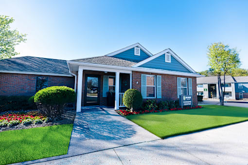 A brick house with a blue roof and a green lawn in front.