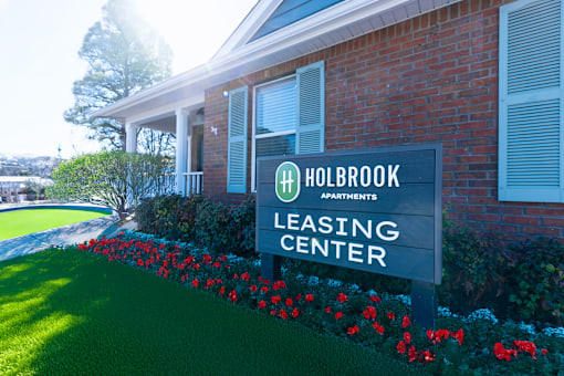 A Holbrook Apartments leasing center sign in front of a brick building.