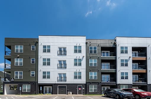 A modern apartment building with cars parked in front.