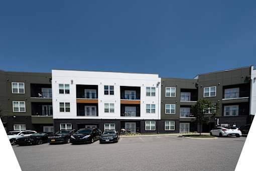 A parking lot in front of a multi-story apartment building.