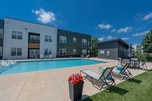 A swimming pool area with lounge chairs and a building in the background.