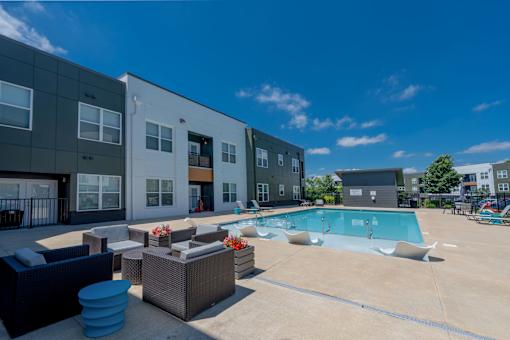 A sunny day at a poolside with a building in the background.