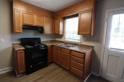 A kitchen with wooden cabinets and a black stove top oven.