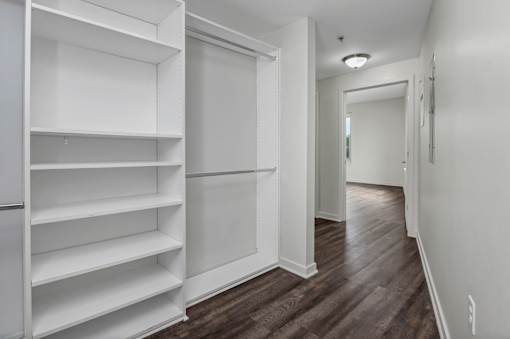 A long hallway with a white door and shelves on the left.