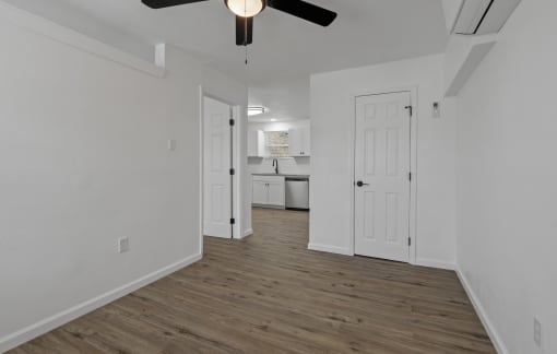 an empty living room with white walls and a ceiling fan