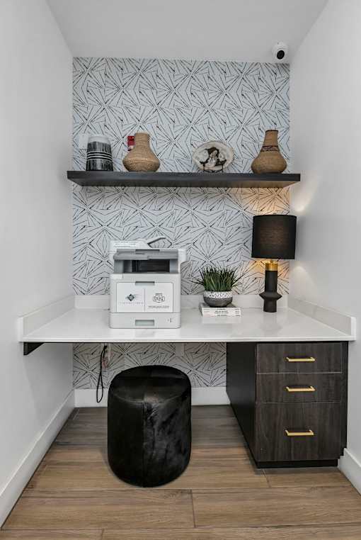 A white desk with a black lamp and a plant on it.