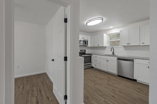 an empty kitchen with white cabinets and stainless steel appliances