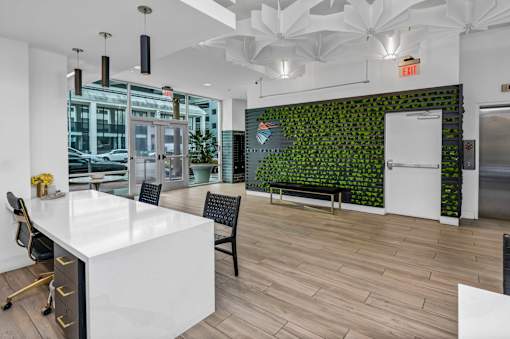 A white desk with a green plant wall behind it.