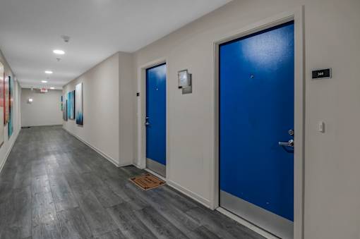 A hallway with blue doors and grey flooring.