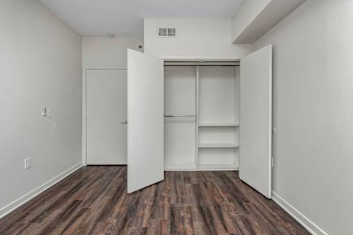A room with a white wall and a white closet with shelves.