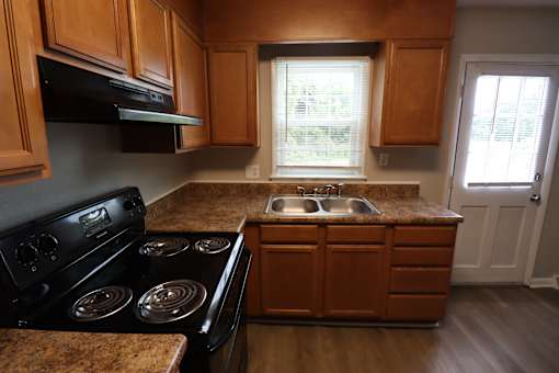 A kitchen with wooden cabinets and a black stove top oven.