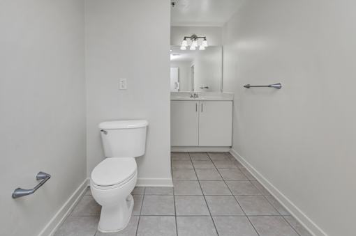 A white toilet in a bathroom with a white cabinet and a mirror.