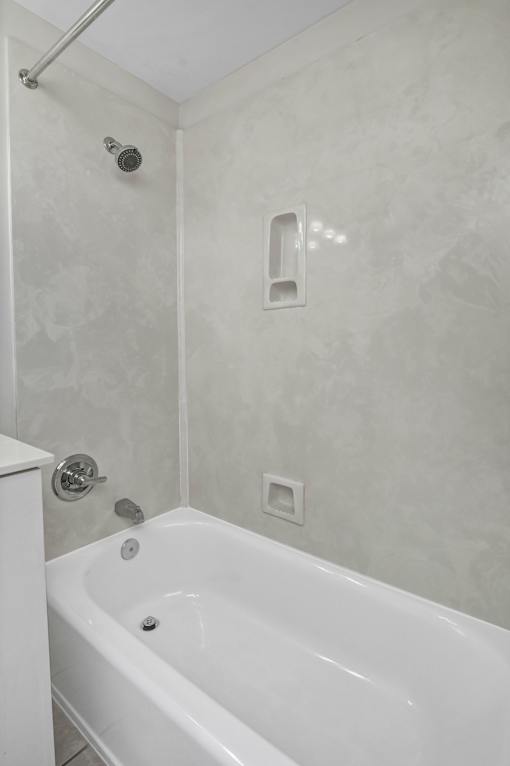 A white bathtub in a bathroom with a shower head and a square drain.