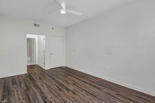 A room with a ceiling fan and wood flooring.