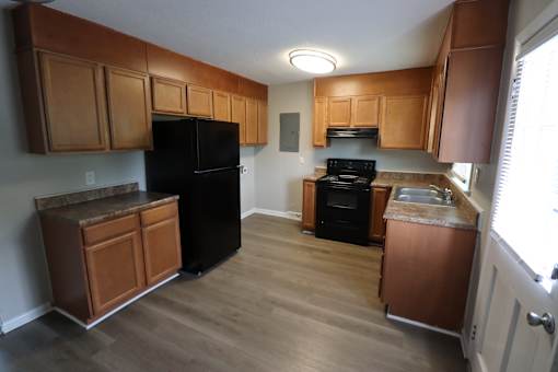 A kitchen with wooden cabinets and a black refrigerator.