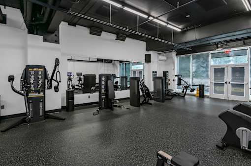 A gym with a variety of equipment including treadmills, weights, and exercise machines.