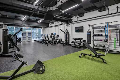 A gym with a variety of equipment including a rowing machine, weights, and a bench press.
